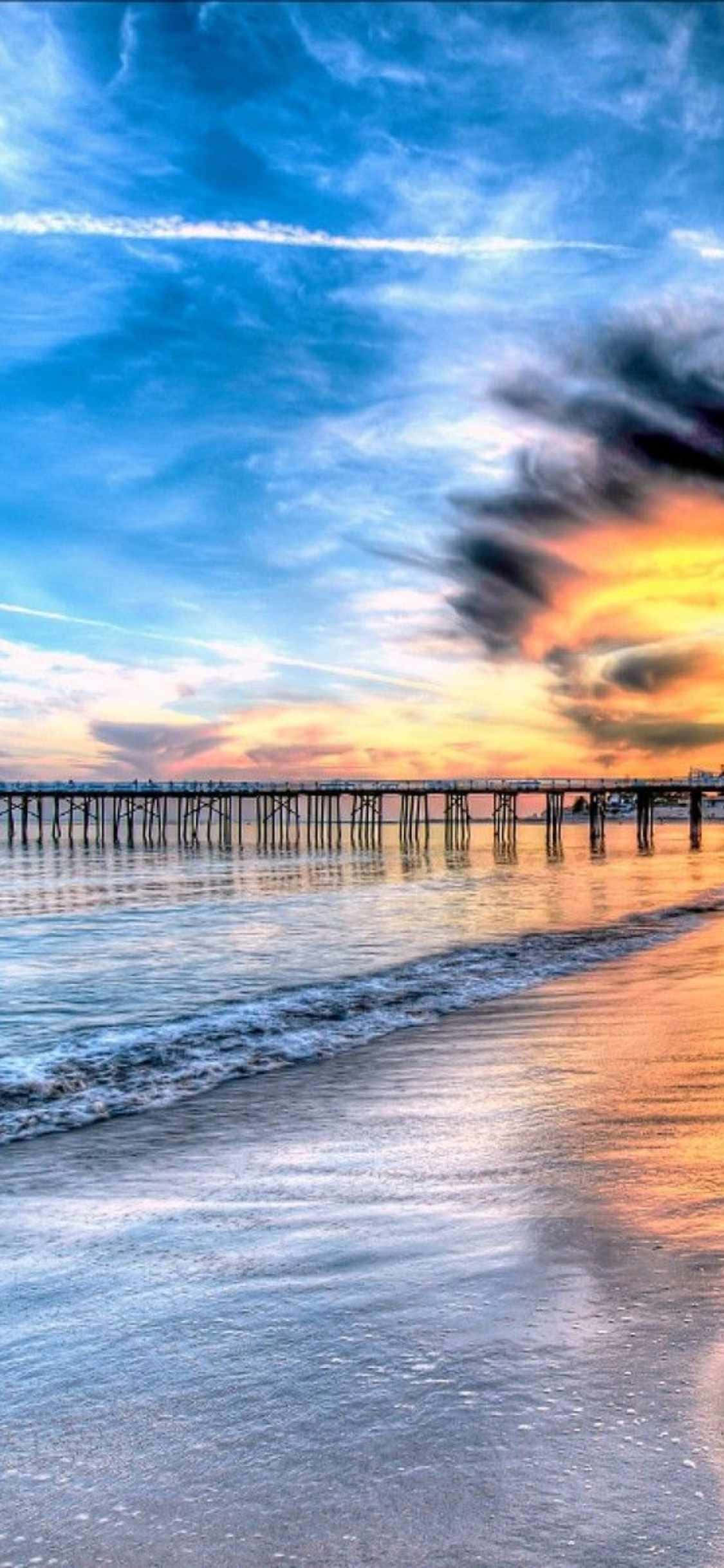 a pier with a sunset over the ocean ওয়ালপেপার