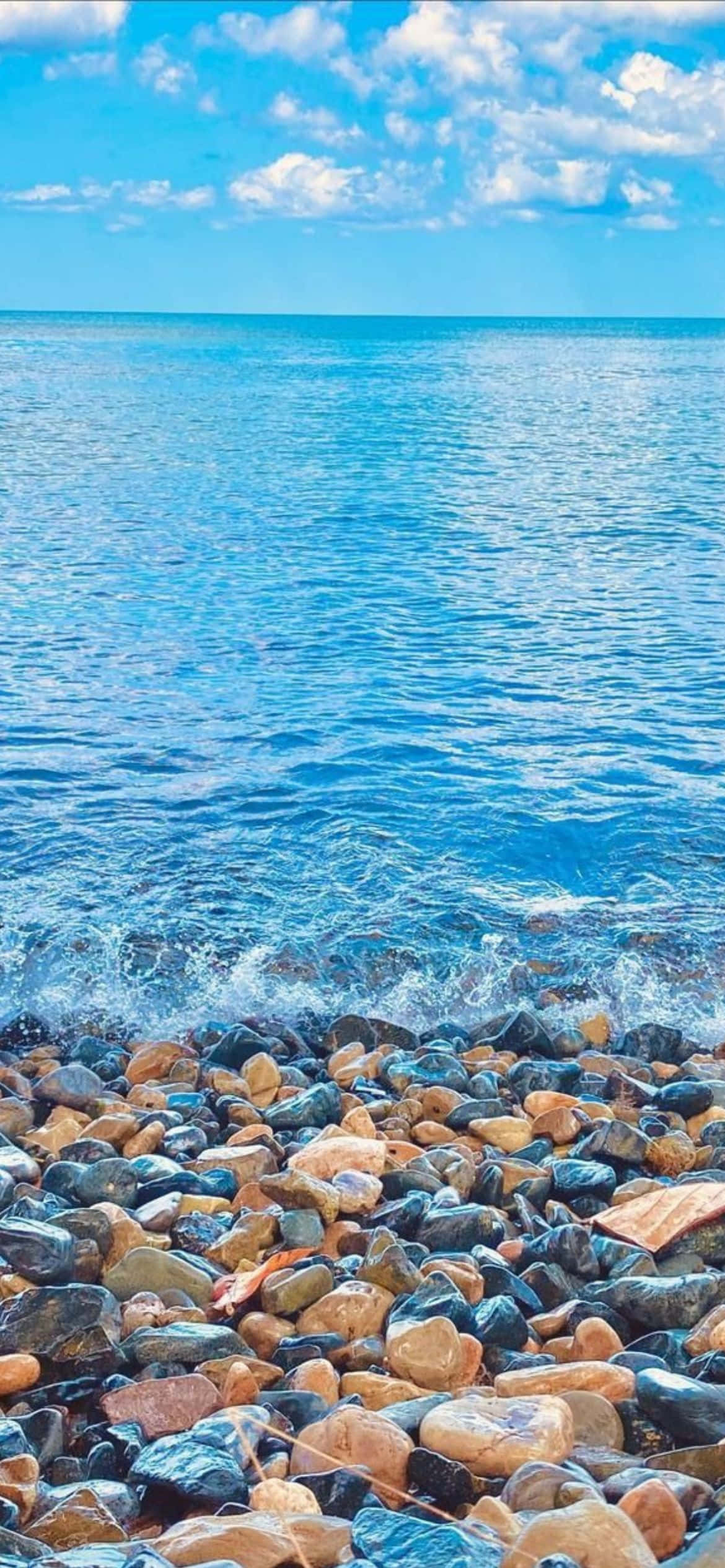 পাথর ও জল সহ একটি সৈকত ওয়ালপেপার